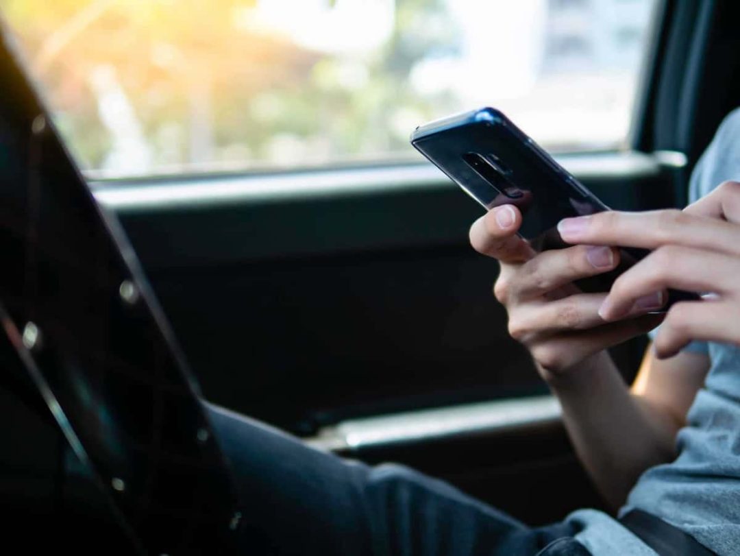 Closeup of hands holding a smartphone inside a car