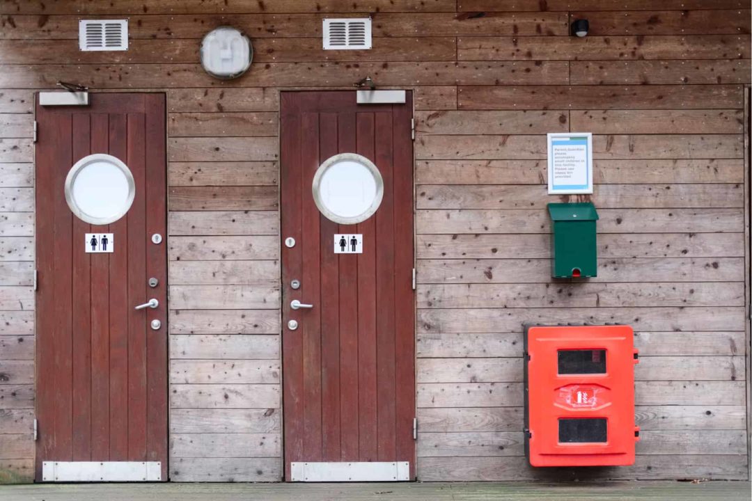 Two public bathroom doors against a wood wall 