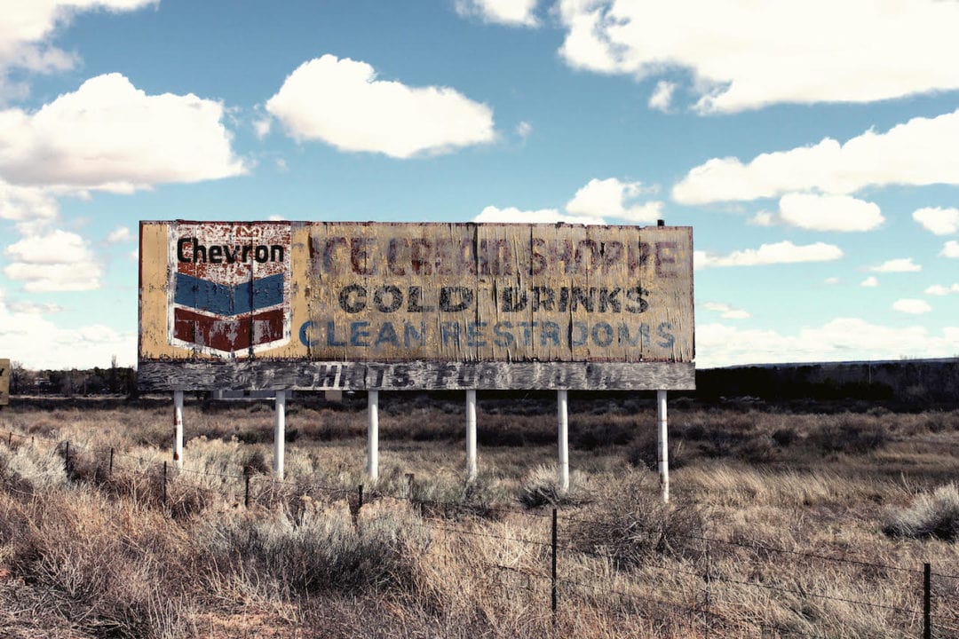 a dilapidated billboard in the middle of dead grass