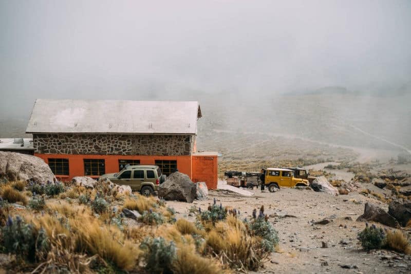 Two vehicles rest parked beside a barn