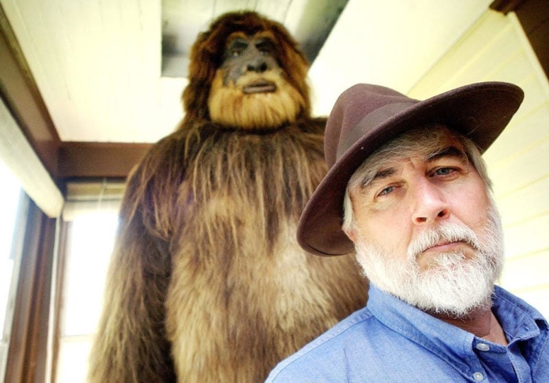 man in hat in front of bigfoot statue