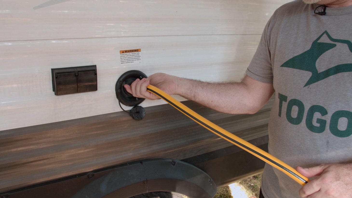 Male hooking up hose to RV water tank