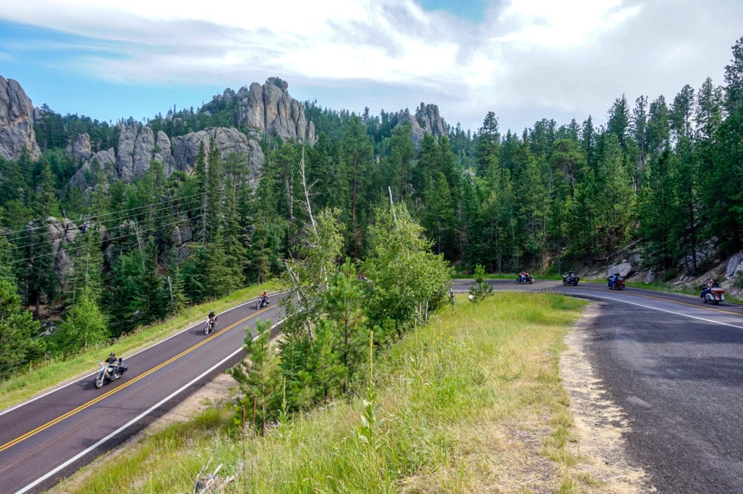 Motorcyclists traveling around a corner on a scenic road