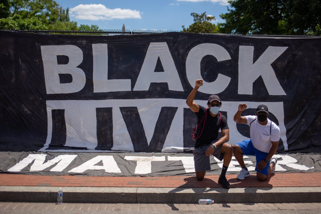 A Black Lives Matter banner blocks out the view of the White House and becomes a popular photo backdrop.