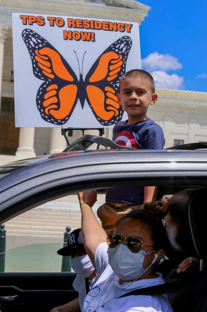 A boy pops out of a sunroof.
