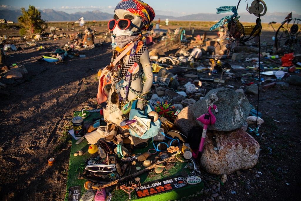 Everything from alien figures, photos, and business cards to pens, keys, toys, and even personal items of lost loved ones fill the garden.