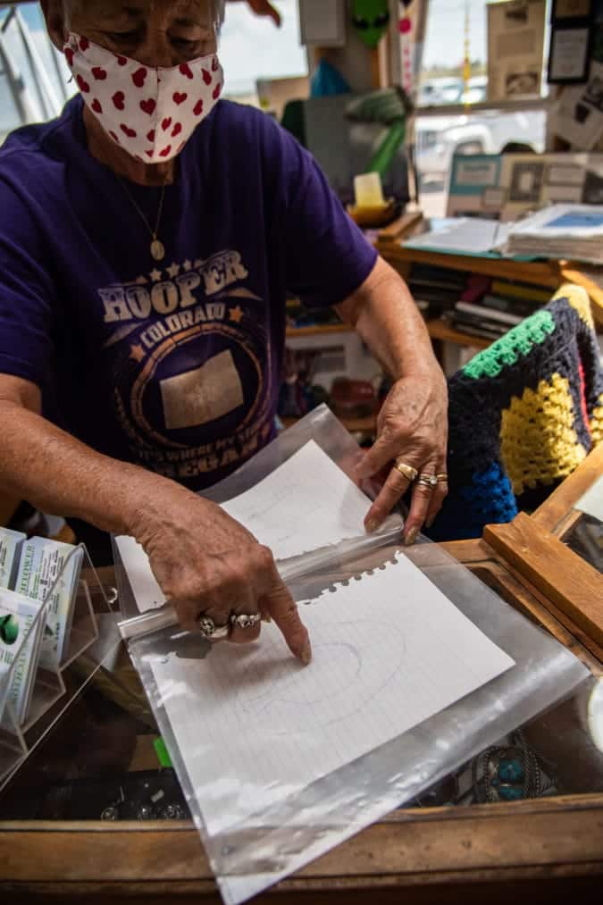 Messoline wearing a mask and pointing at a psychic's drawing