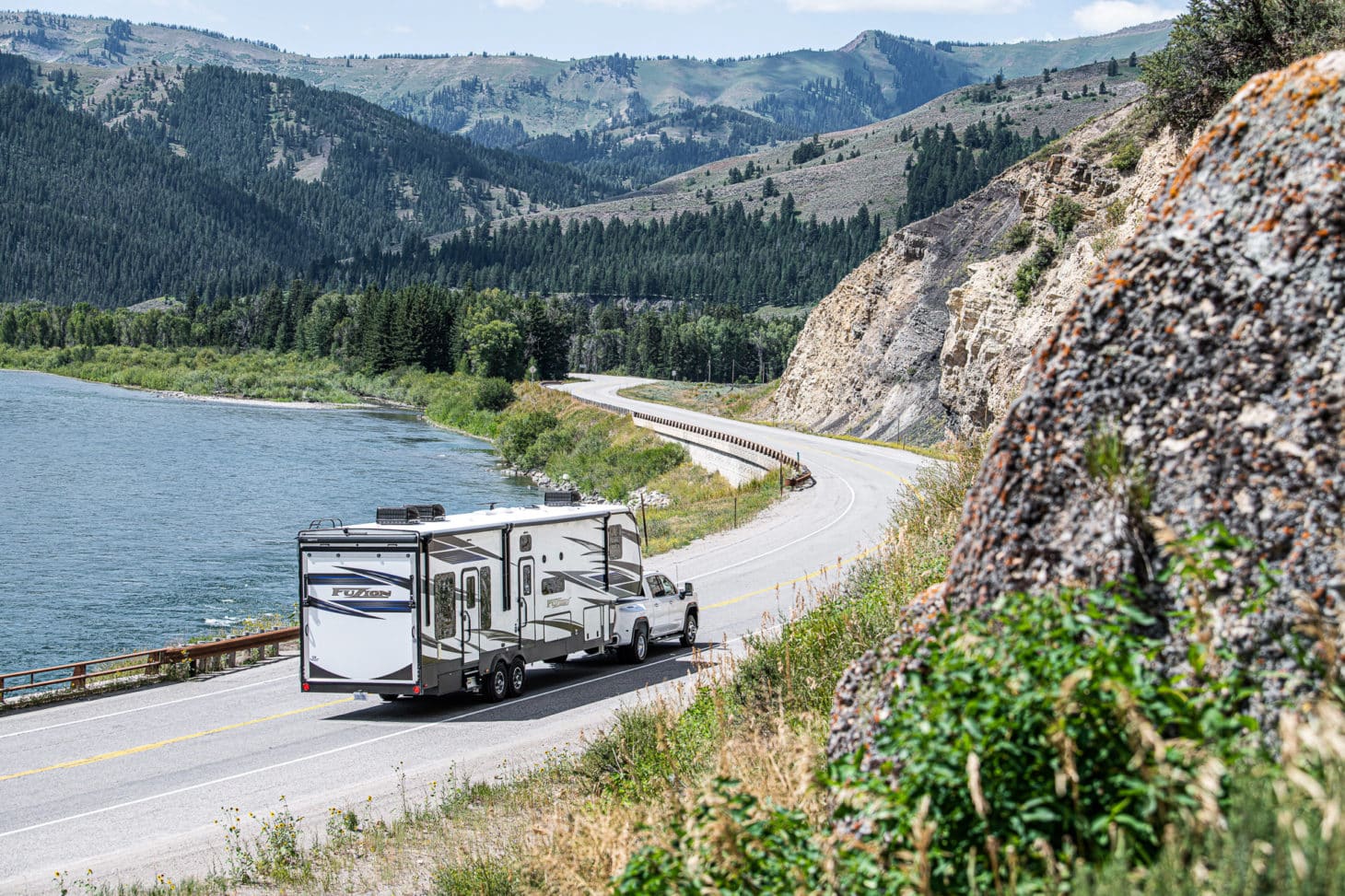 Toy hauler travel trailer being towed by a pickup truck through winding road