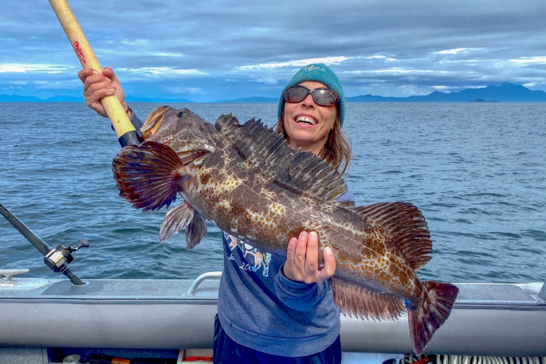 A woman on a boat holding a large fish