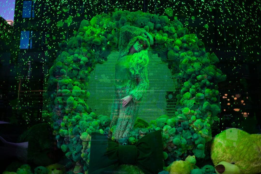 At Bloomingdale’s, a wreath made of green teddy bears encircles a monochromatic mannequin outfitted in her holiday best.
