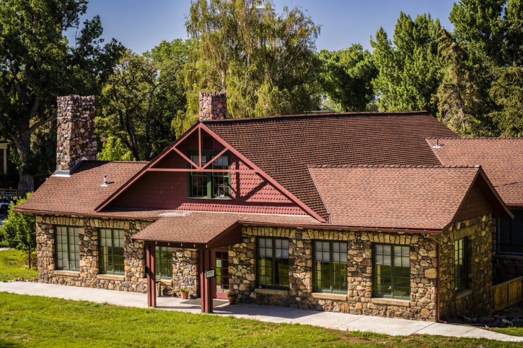 A stone building surrounded by lush greenery in the summer.
