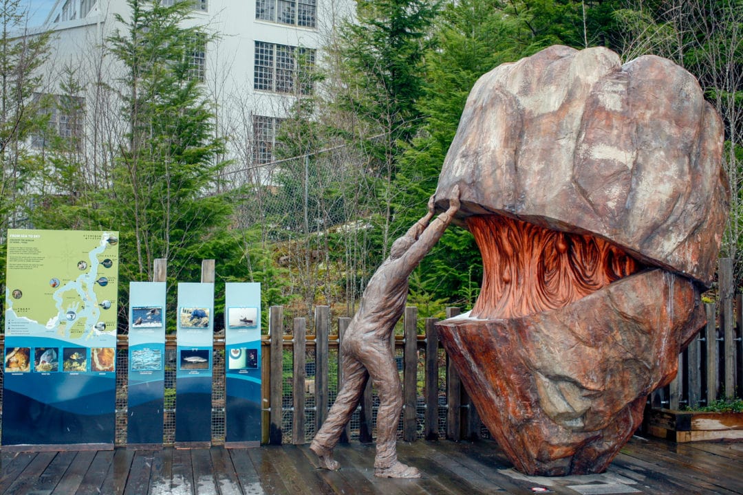 an outdoor statue of a man opening a mountain