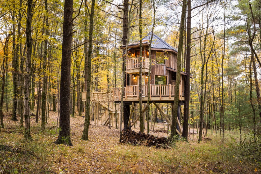 A two-story wooden treehouse in the woods