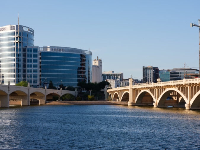 View of a river with two bridges over the water and modern glass buildings in the background and cityscape in the background