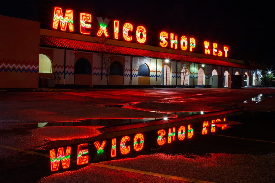 a souvenir shop at night with a reflection in a puddle on asphalt