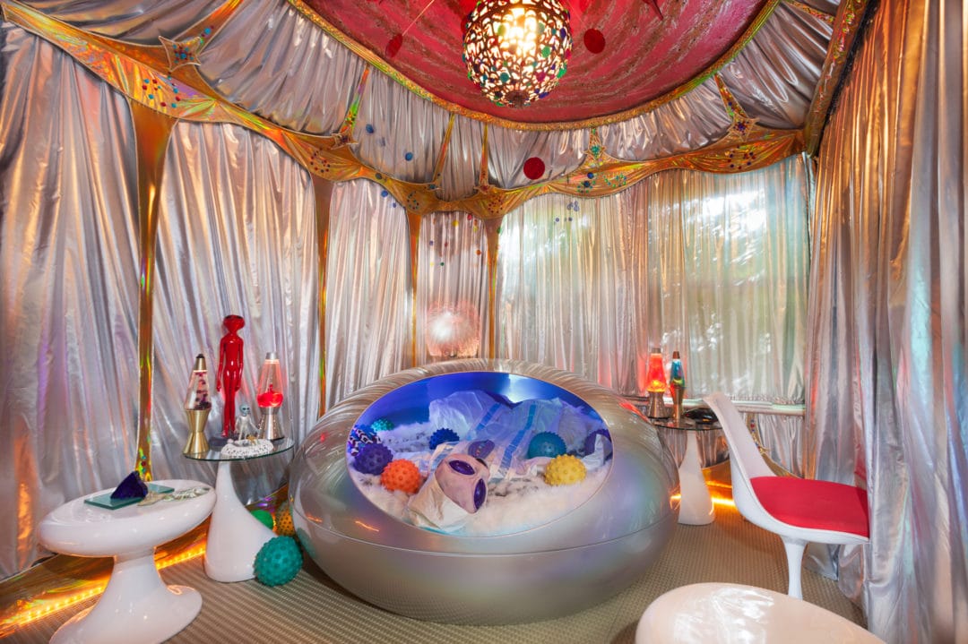 A futuristic looking room covered in metallic fabrics and lava lamps