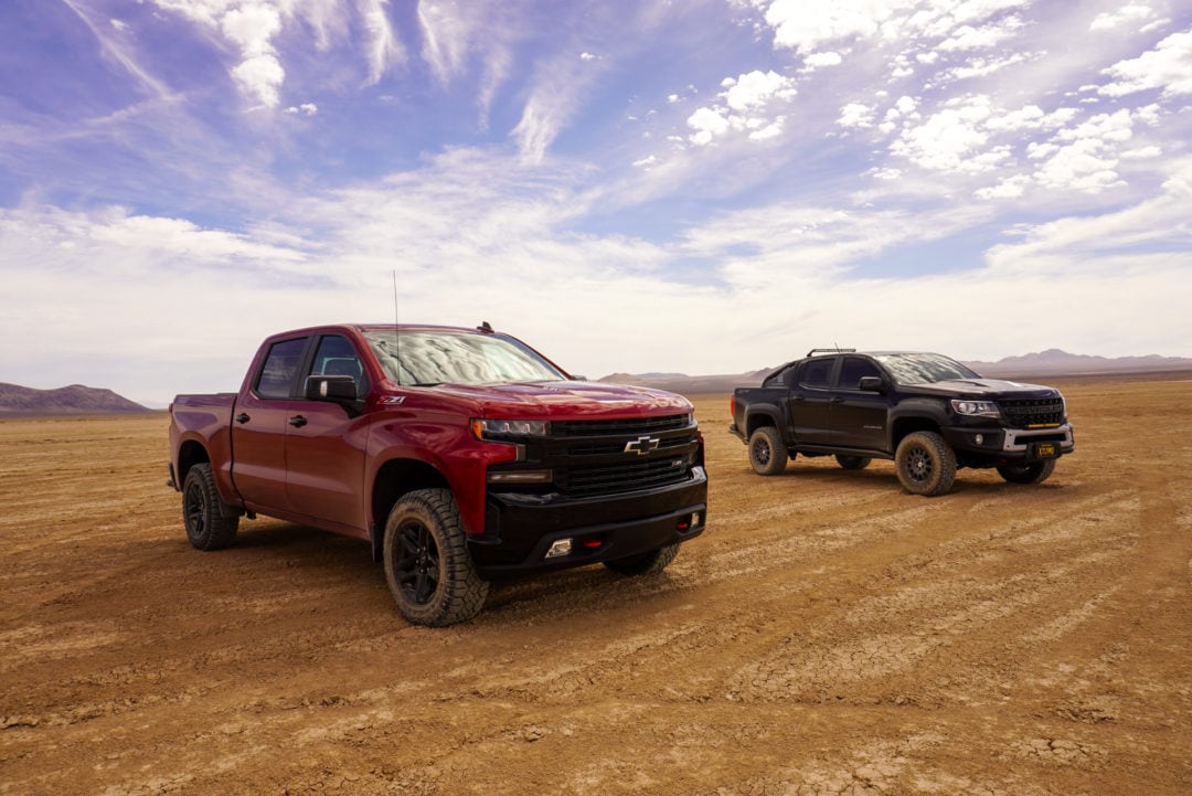 Two Chevrolet pickup trucks parked on a dry desert lake bed