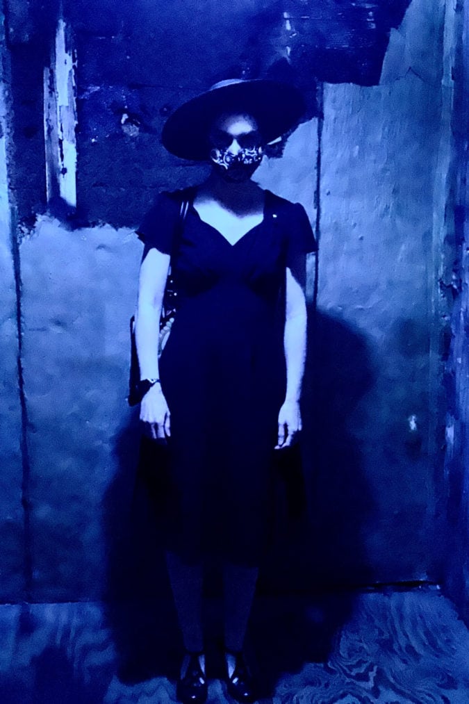 a woman wears a hat, sunglasses and face mask