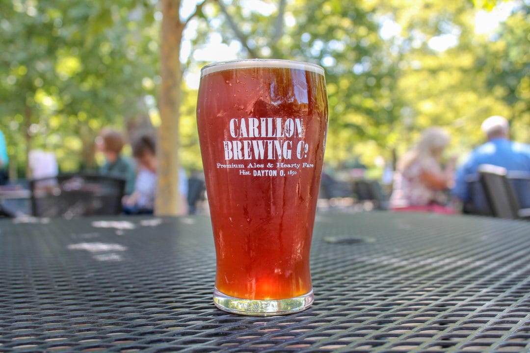 Full pint of red-orange colored beer sitting on outdoor table
