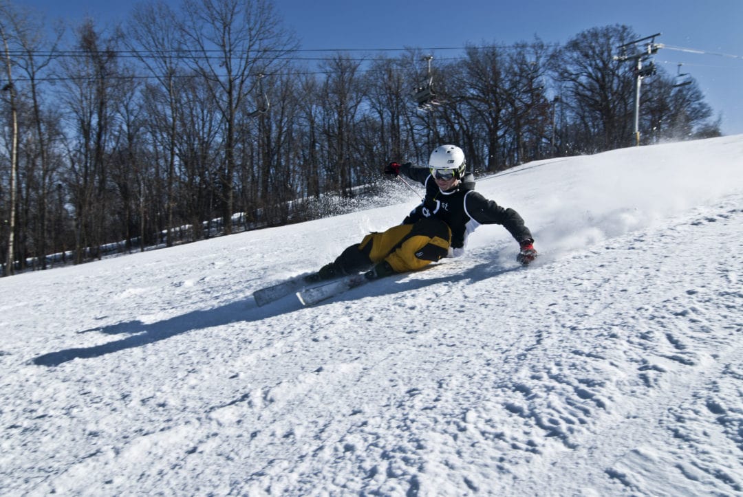 Skier racing down a snowy run at Cascade ski area.