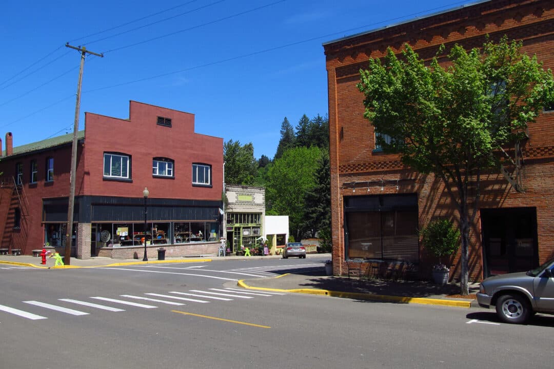 two red brick buildings on a deserted street in a small town set against a blue sky