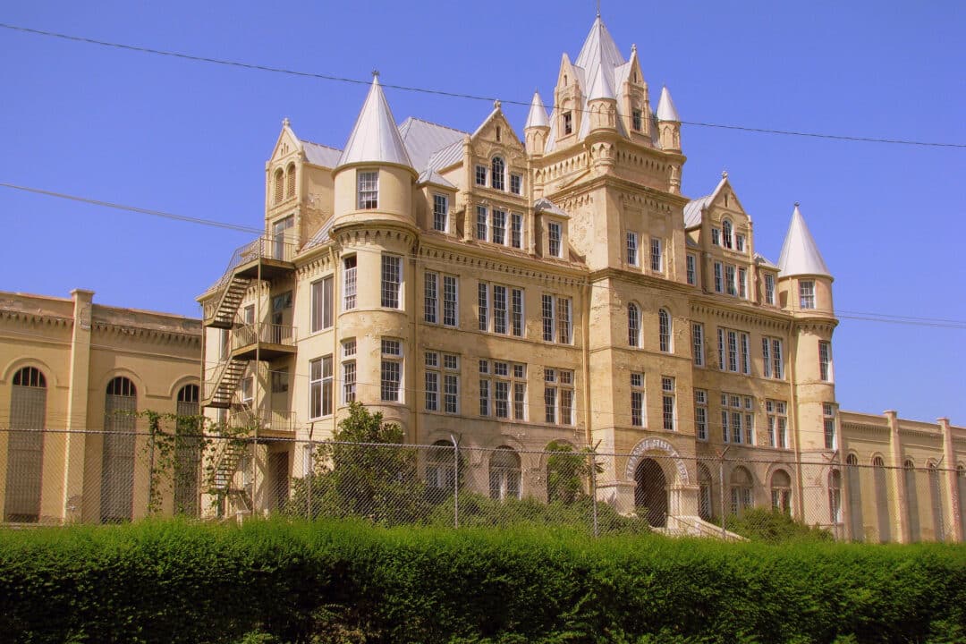 The exterior of Tennessee State Prison, a large, imposing, castle-like structure surrounded by a fence and set against a blue sky