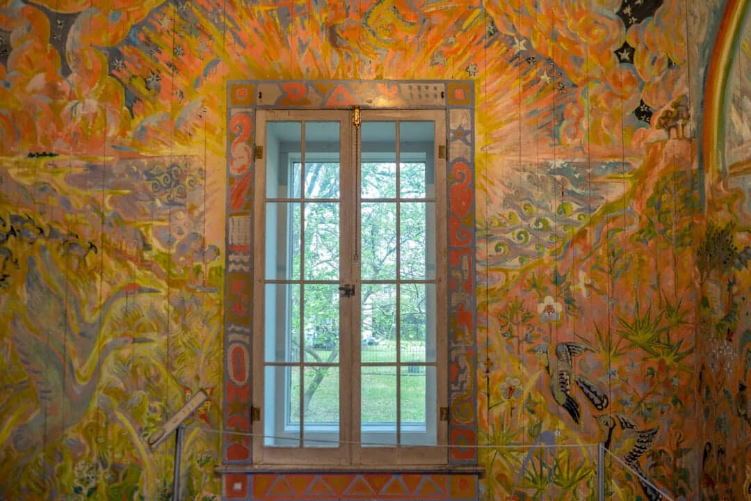 a brightly colored painting on a wall with a window in the center