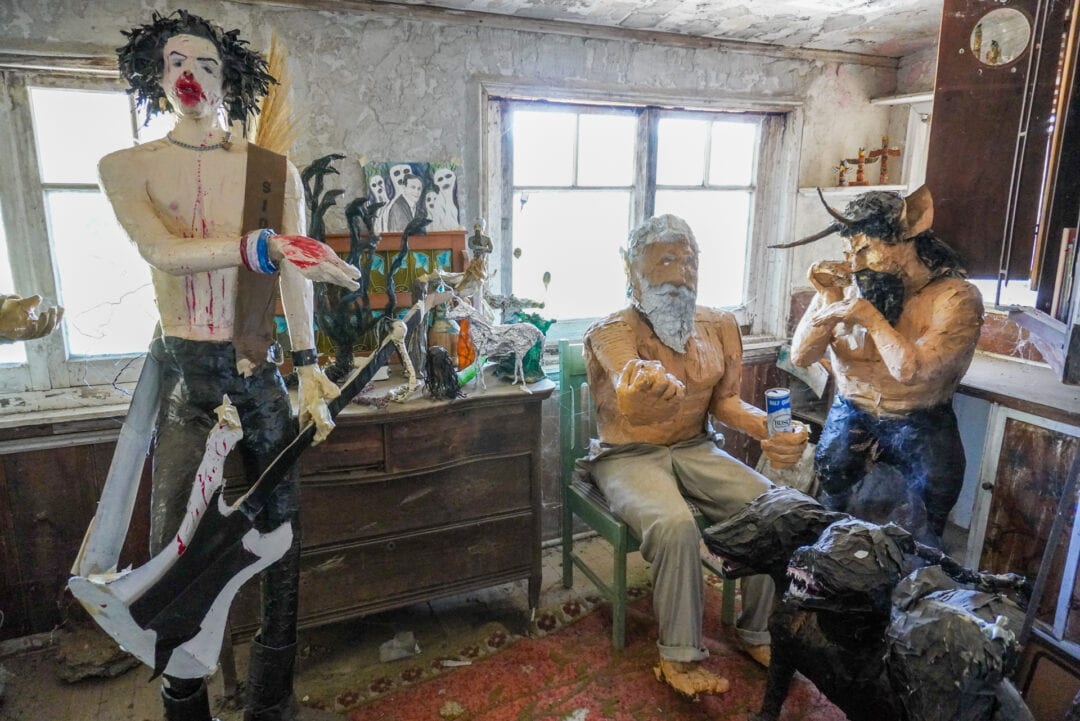 Life-size papier-mâché sculptures inside a small room