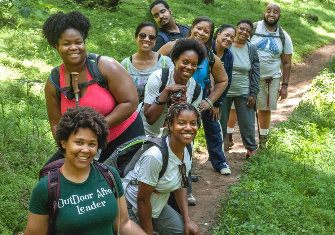 a group of people in hiking gear pose for a group photo outside