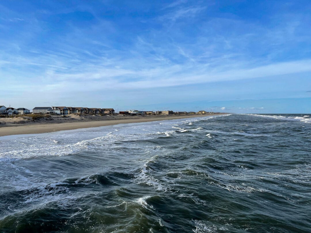 Small waves approaching sandy beach lined with houses