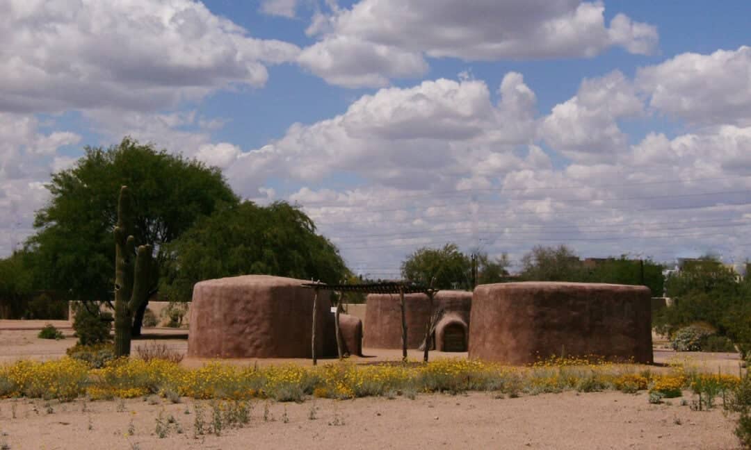 ancient pit houses in the desert underneath a blue sky