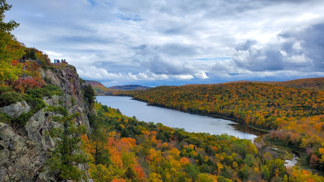 a sweeping aerial view of fall foliage and a lake porcupine mountains