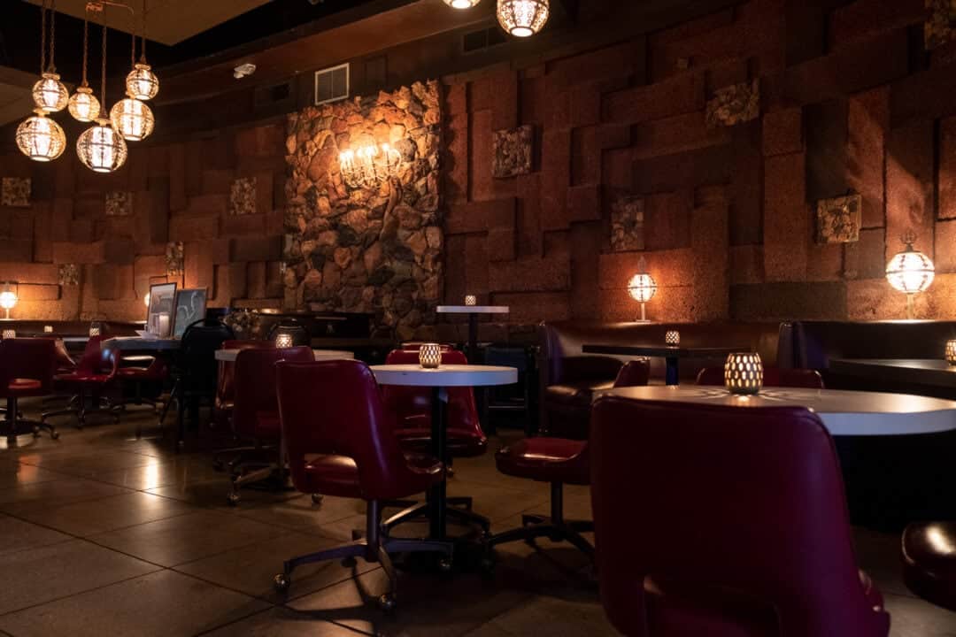 the interior of a restaurant with red chairs, white tables and ball light fixtures