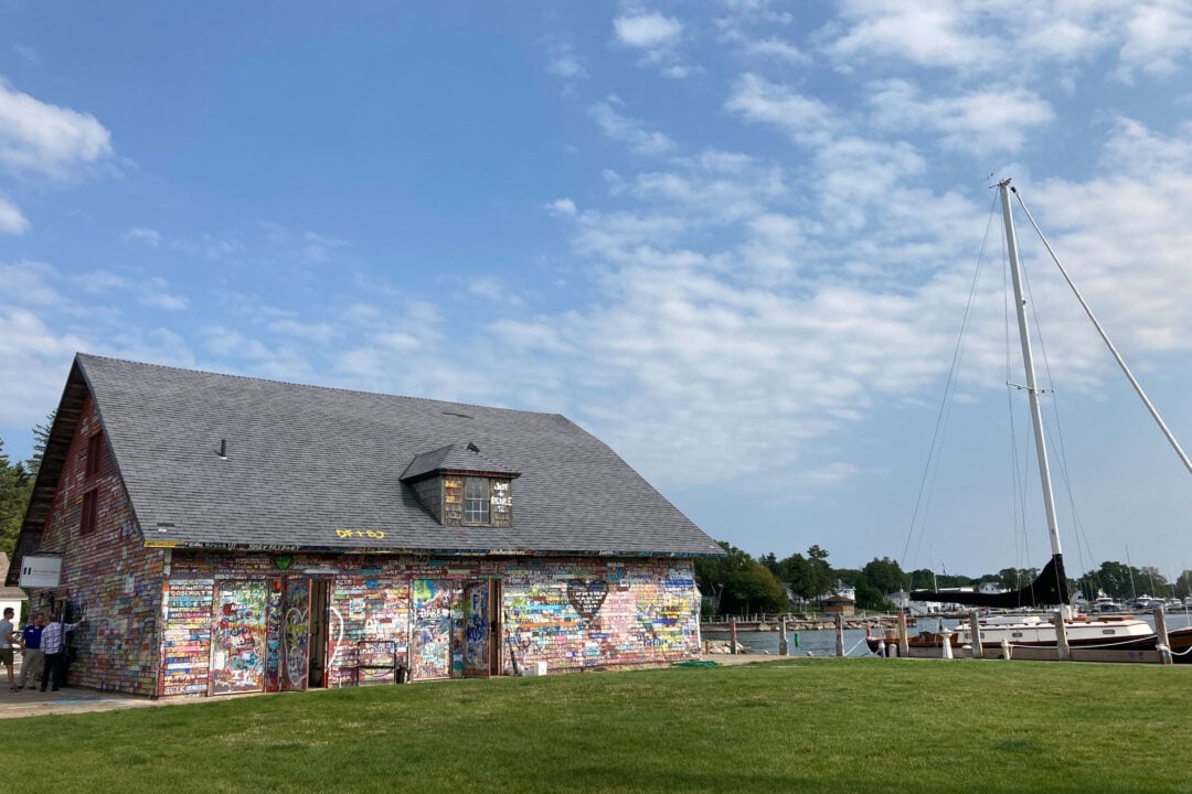 a structure painted in bright colors sits next to the water with boats under a blue sky