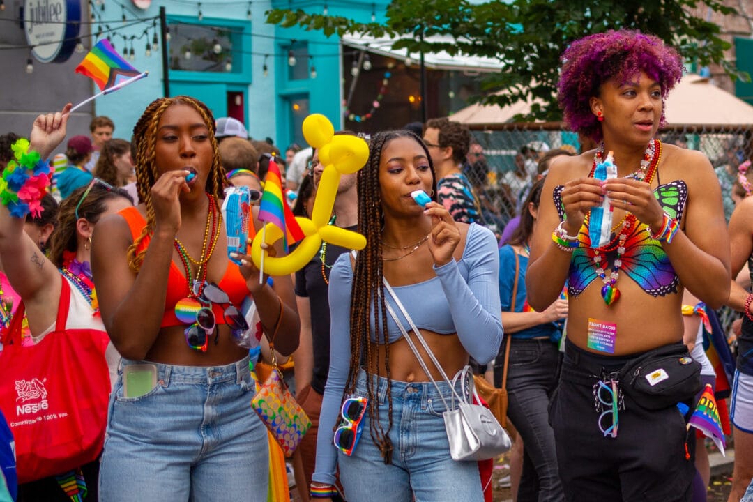 a crowd of colorful spectators watches a pride parade