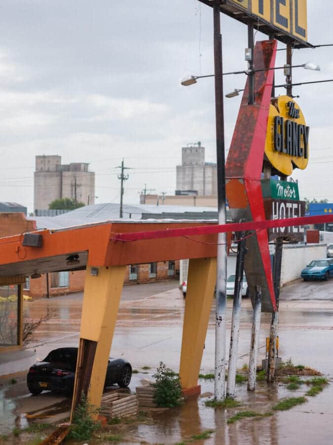 a car is parked under the awning of a motel during a rainstorm