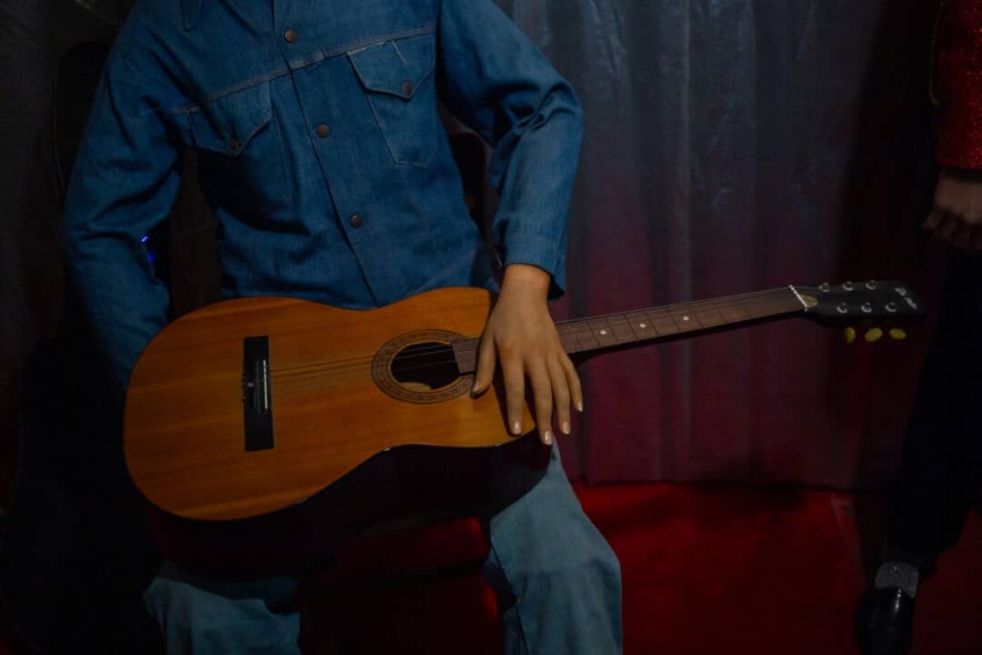 a wax figure holds a guitar