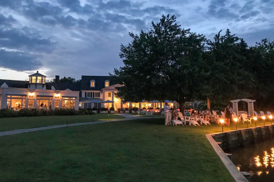 a large inn at sunset with chairs and lights surrounding water