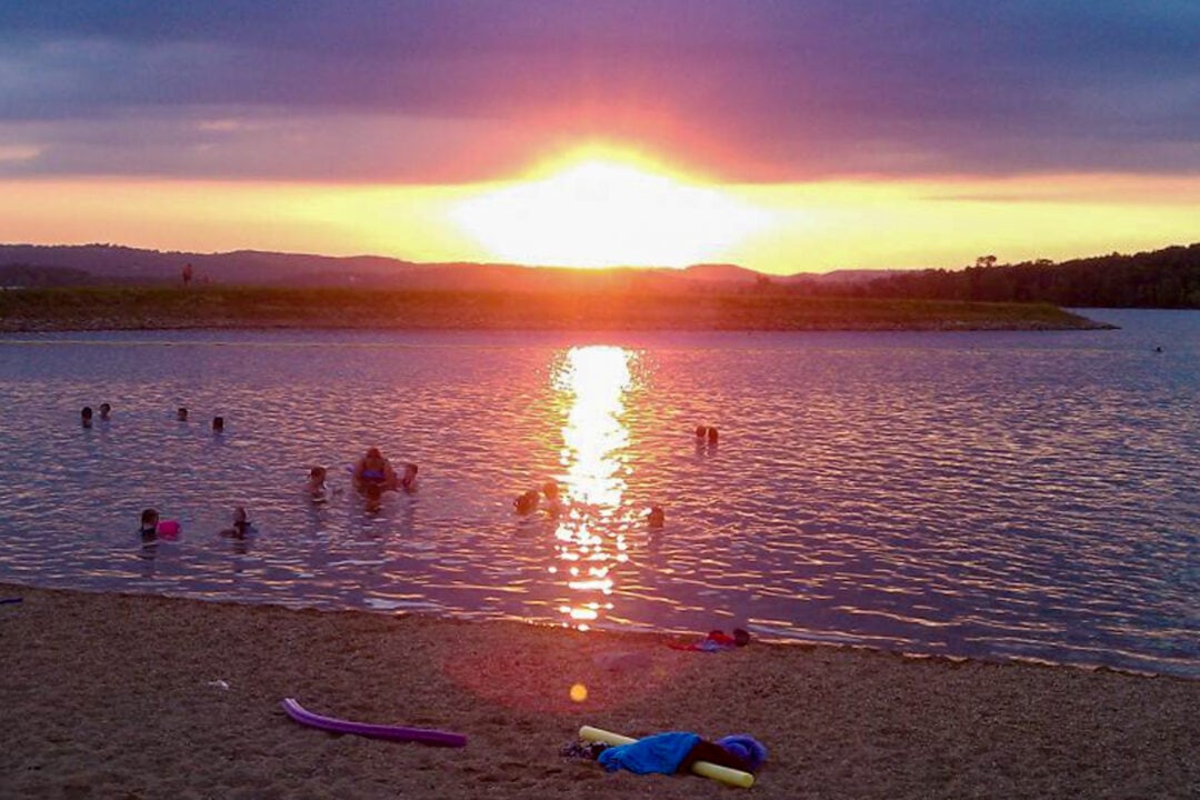 a beach and water at sunset under purple clouds