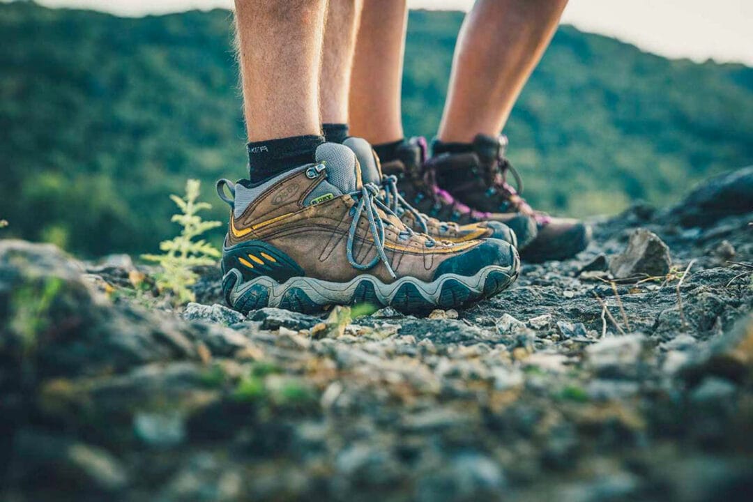 close-up on two pairs of legs in hiking boots on a trail
