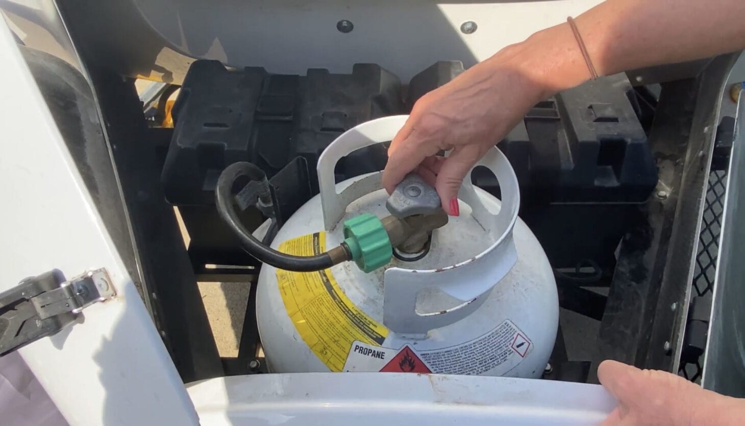 Hand reaching to adjust propane tank