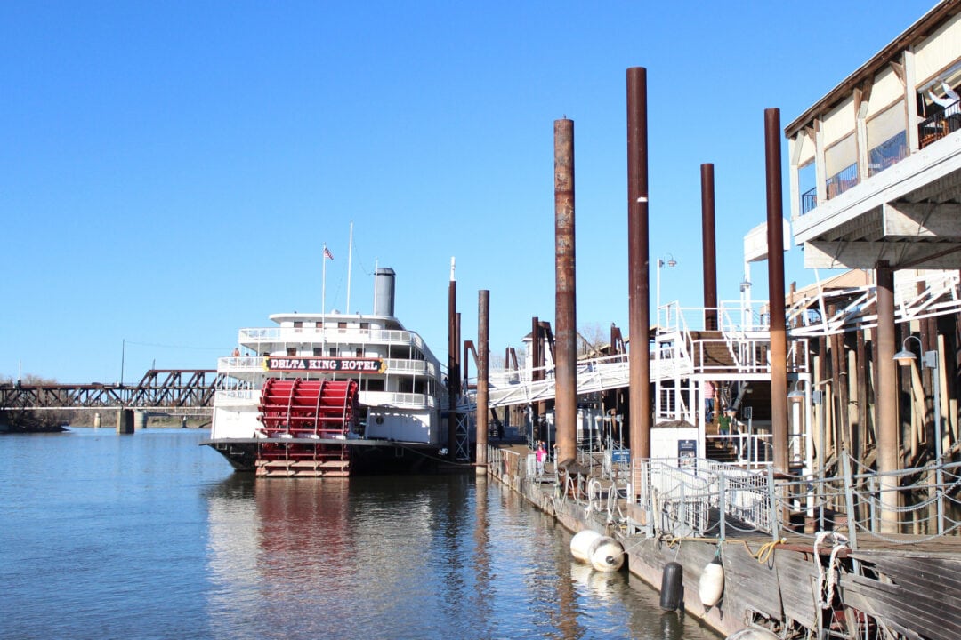 The Delta King Hotel river boat floats on the water near a dock in a marina