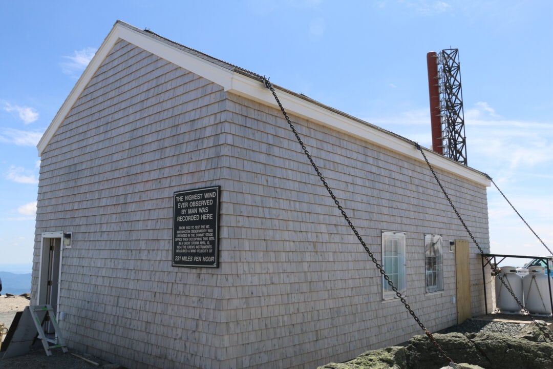 a grey shingled building at the top of a mountain