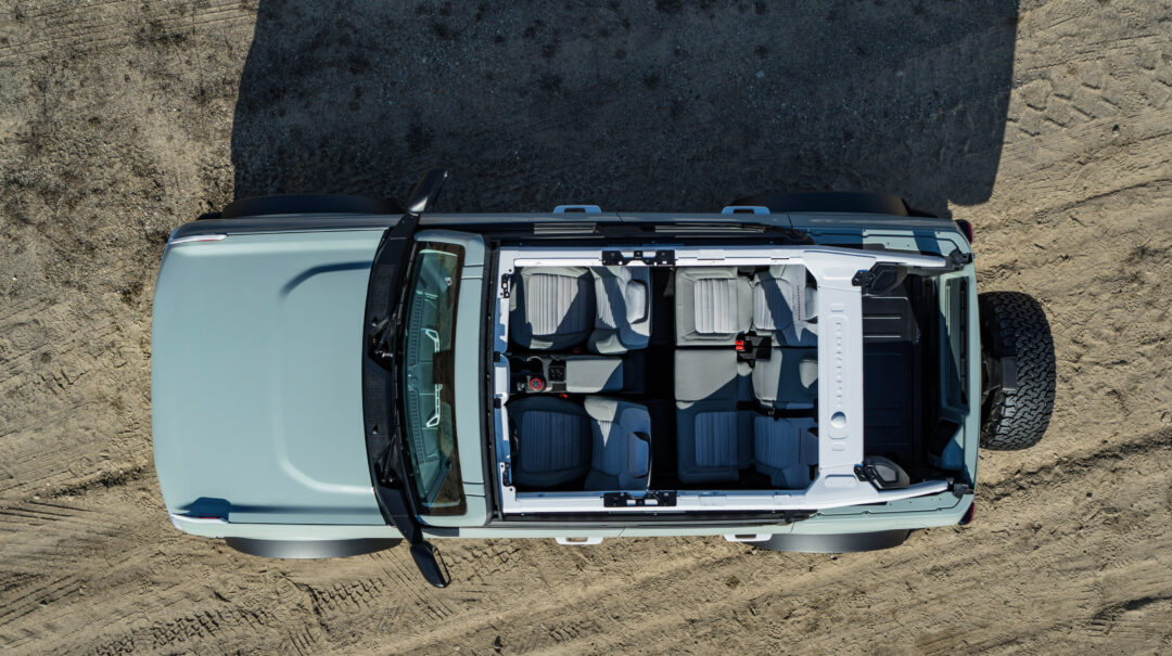 an aerial overview shot of a ford bronco with the top off on a dirt road