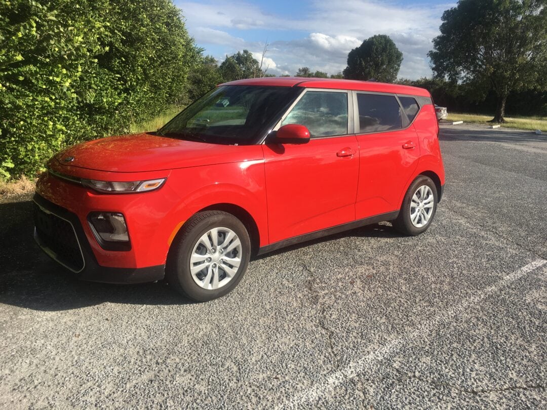 a red small car parked in a parking lot