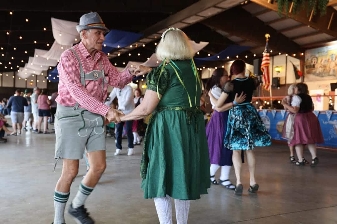 people in lederhosen dance in a hall