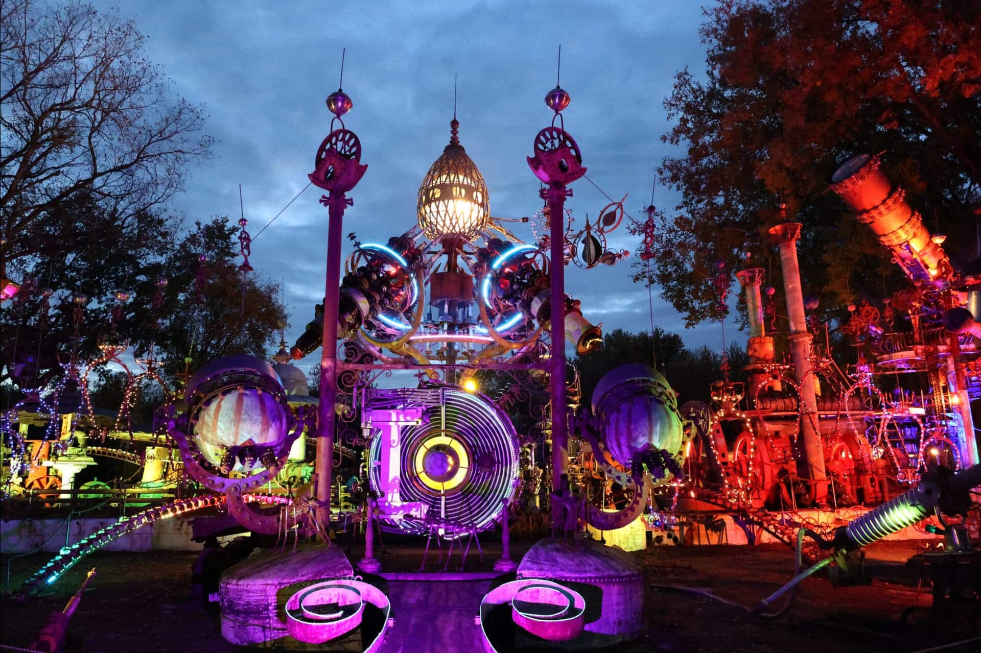 a sprawling metal sculpture lit up in purple and red lights at night