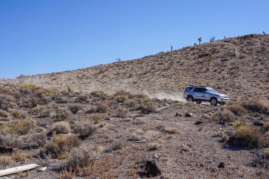 An off-road vehicle traveling down a dirt road in a desert landscape
