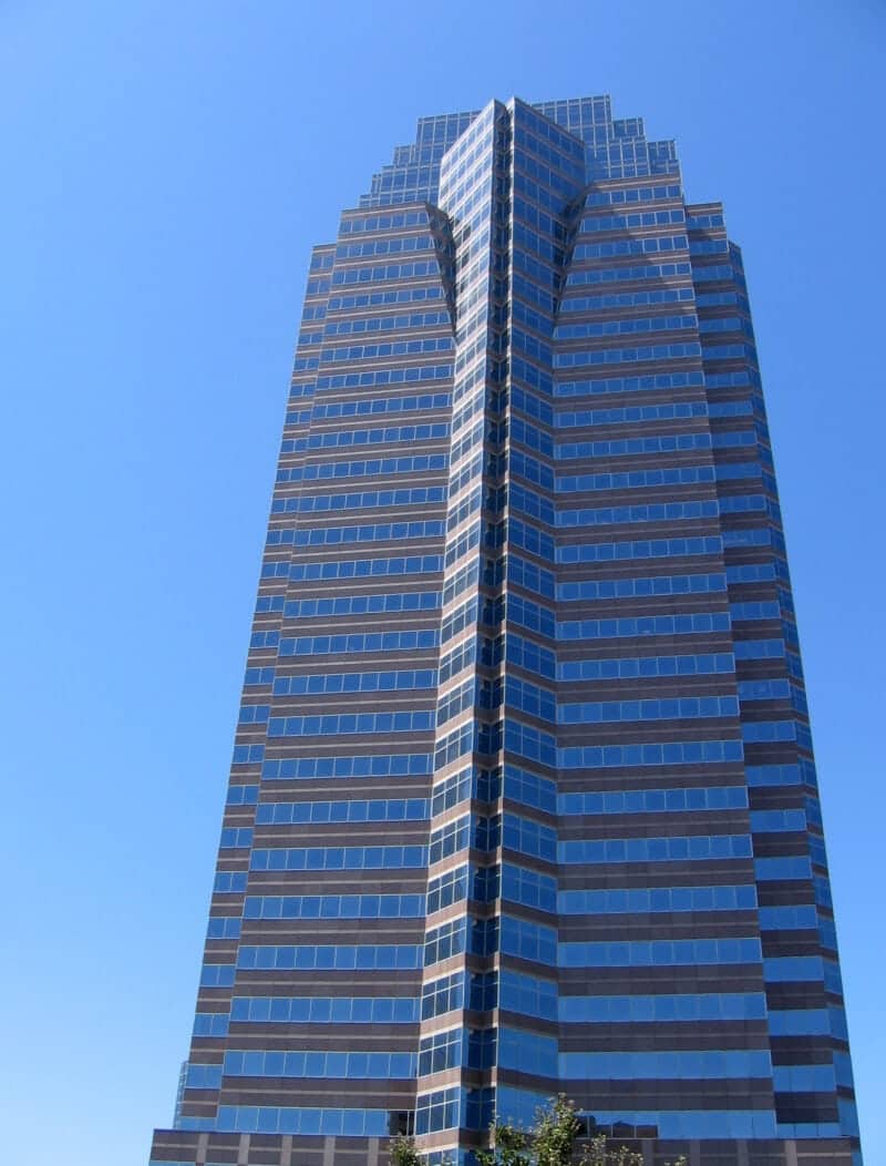 a tall glass and steel angular office building set against a clear blue sky