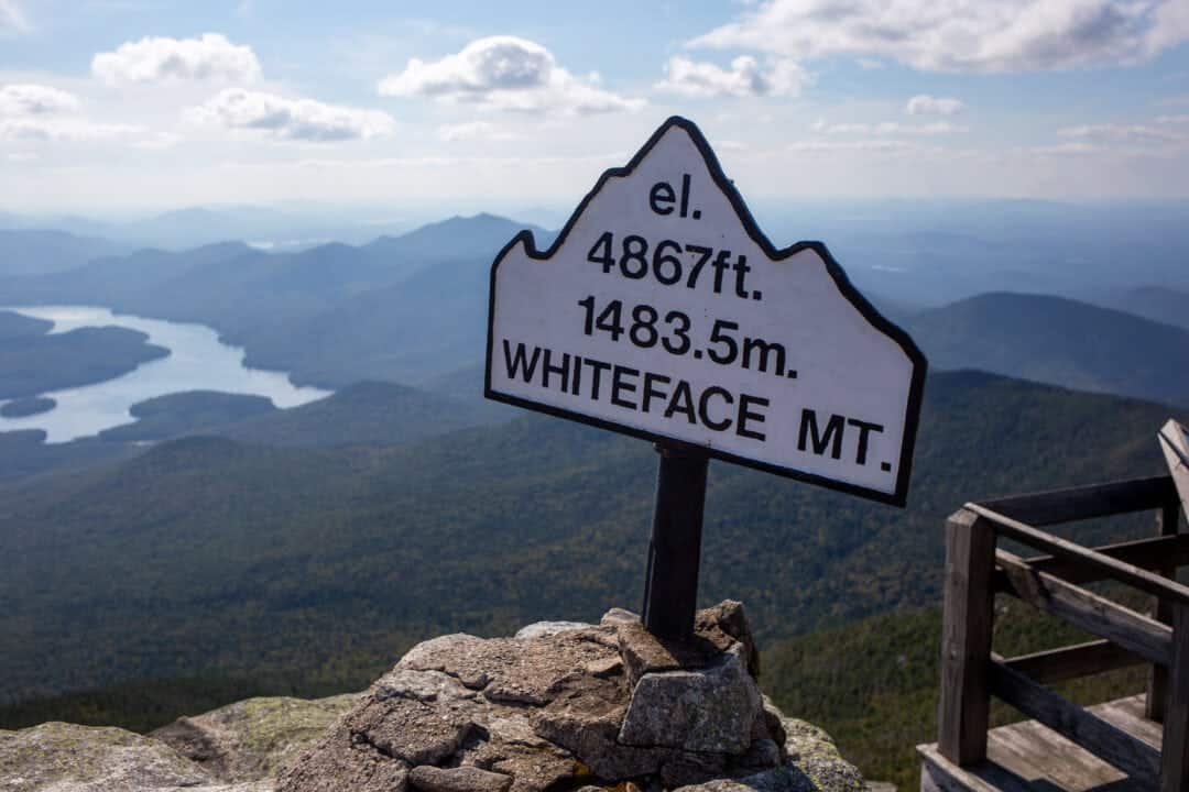 a sign that says "el. 4967 ft. 1483.5 m. Whiteface Mt." on a scenic overlook